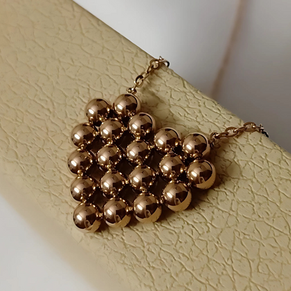 Gold beaded necklace on a textured beige surface