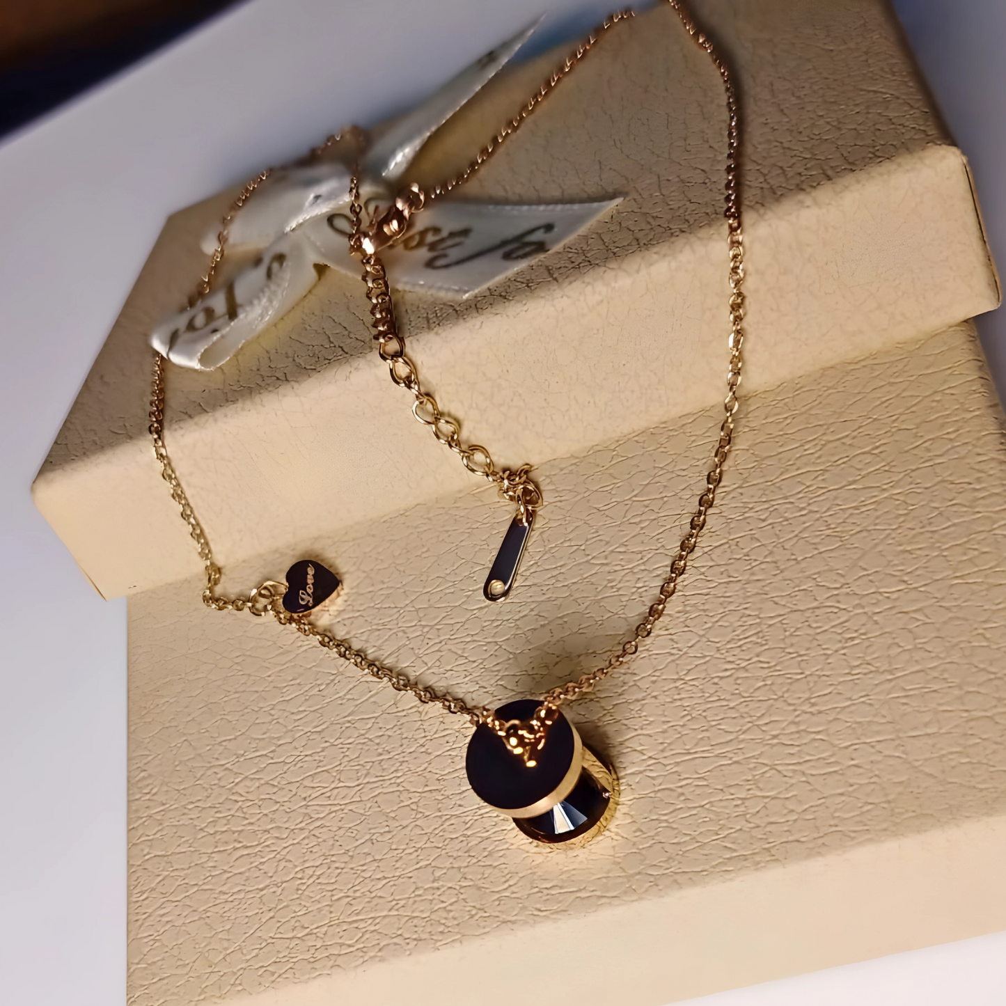 Gold necklace with black accents on a beige jewelry box