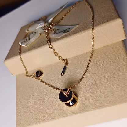 Gold necklace with black accents on a beige jewelry box