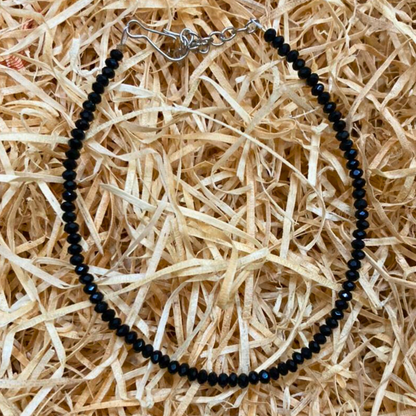 Black beaded necklace on a bed of straw