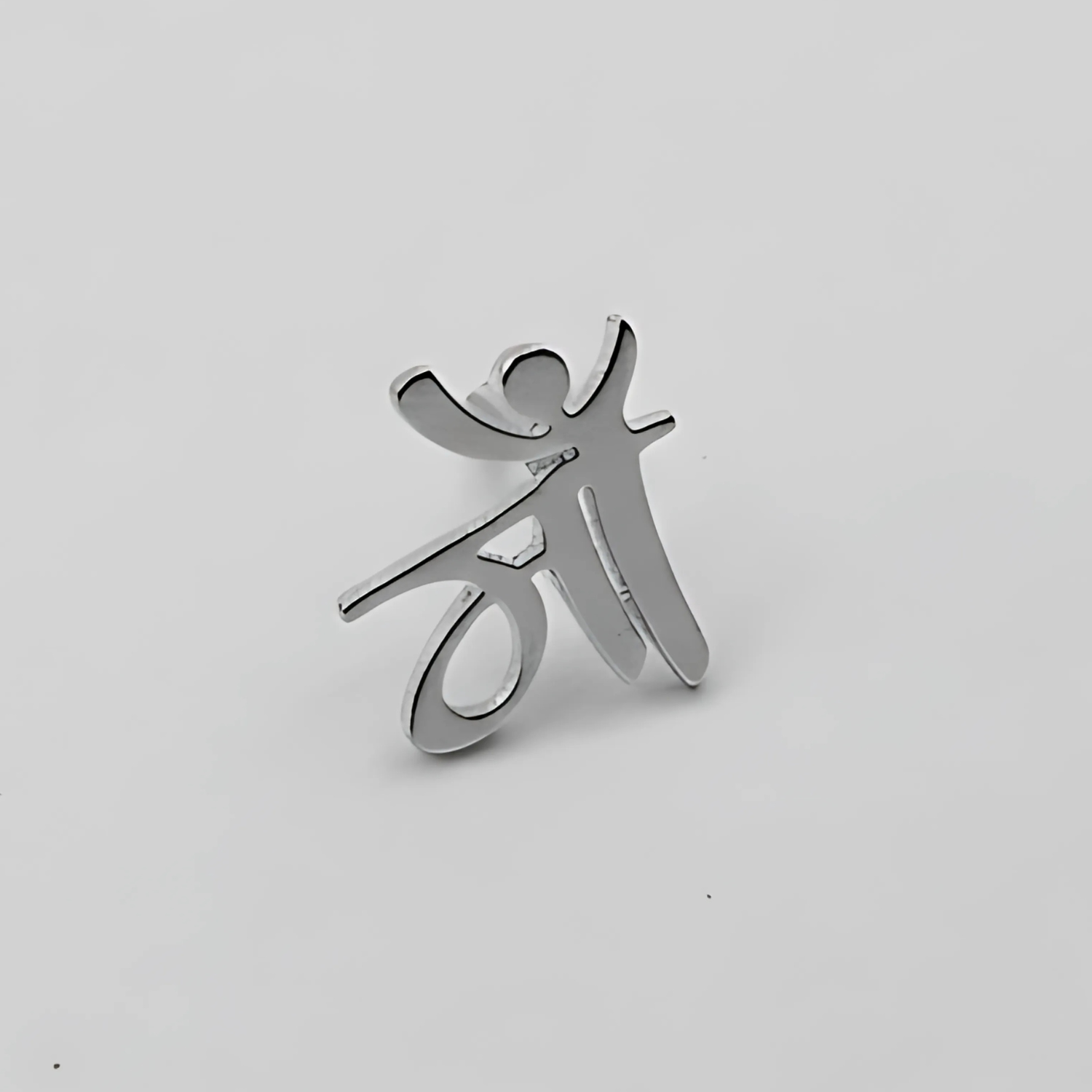 Silver pendant shaped like a stylized person on a light gray background