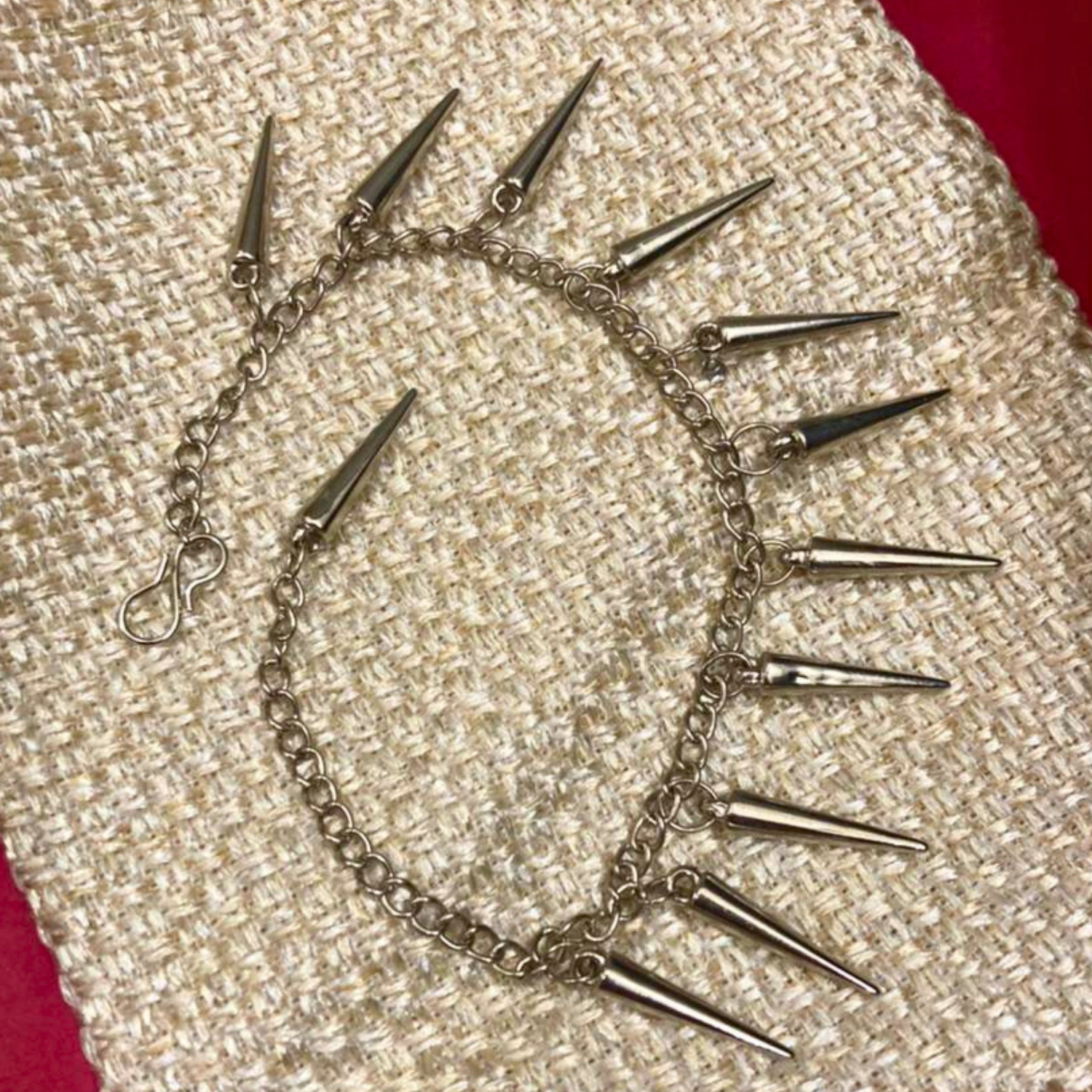 Silver chain choker with spikes on a textured beige surface