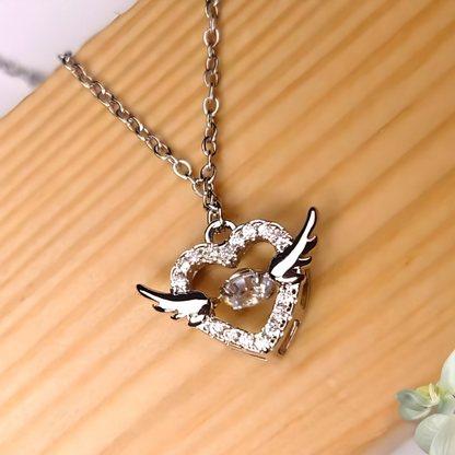 Silver necklace with a heart and bird pendant on a wooden surface