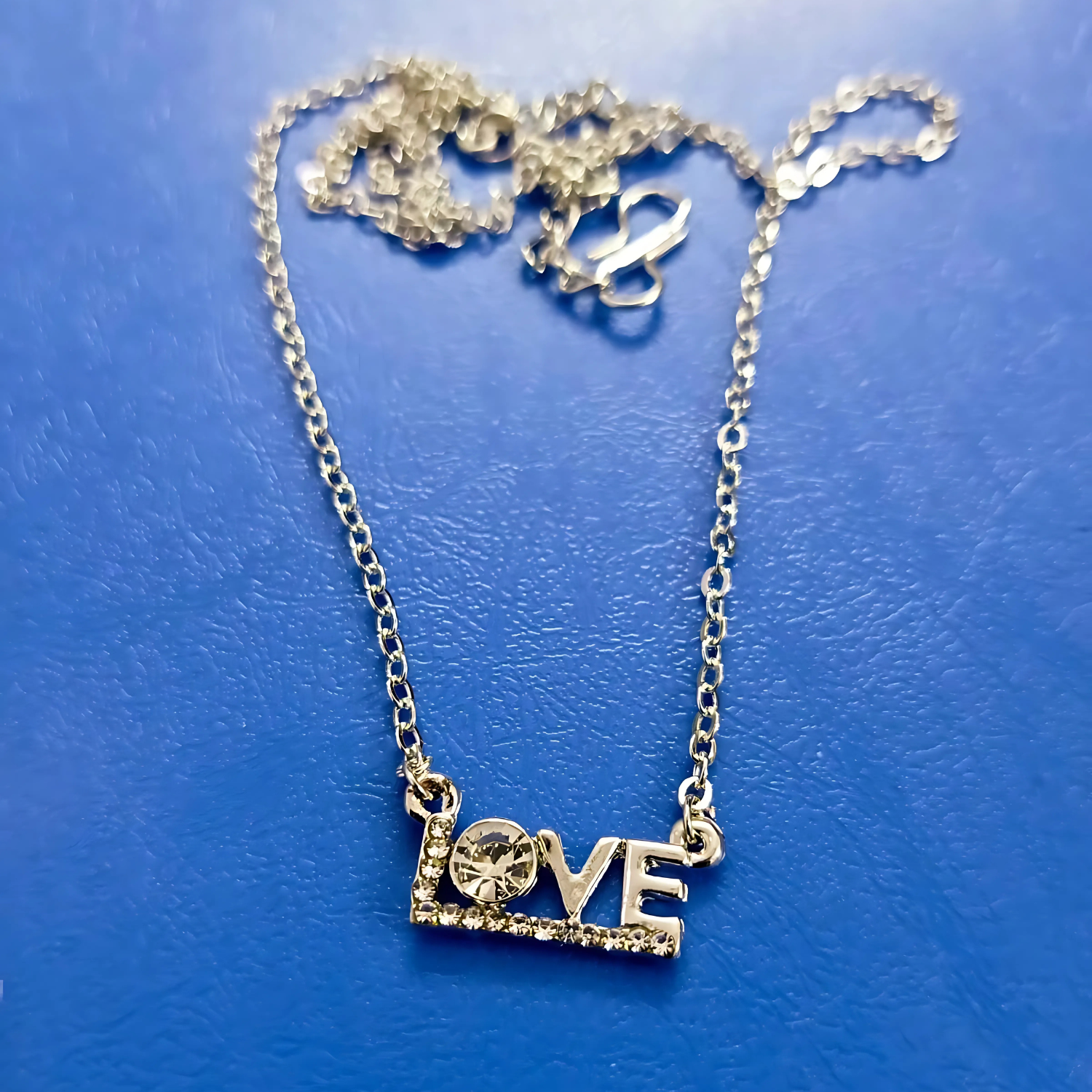 Gold 'LOVE' necklace on a blue background