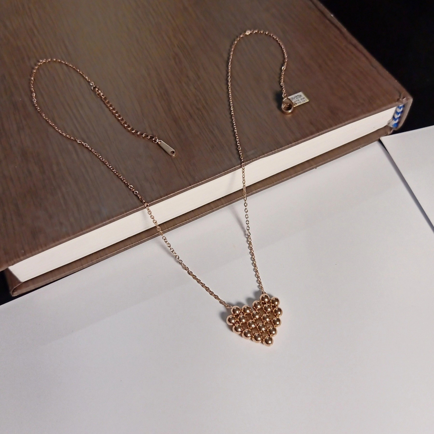 Rose gold necklace with a heart pendant on a wooden surface
