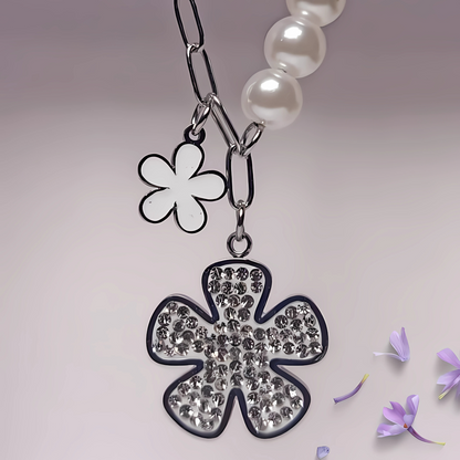 Necklace with a clover-shaped pendant and flower charm on a light background
