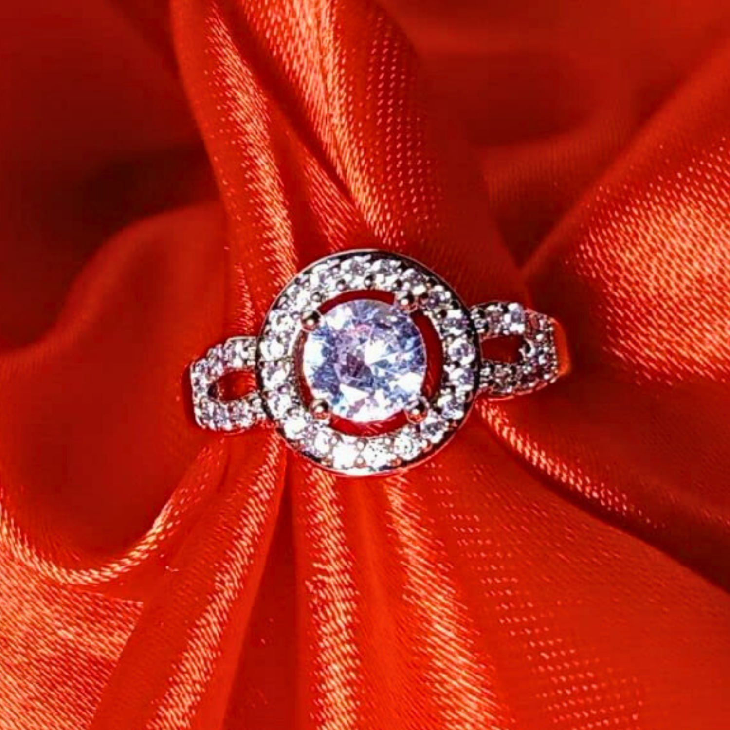 Silver ring with a large central gemstone on a red fabric background