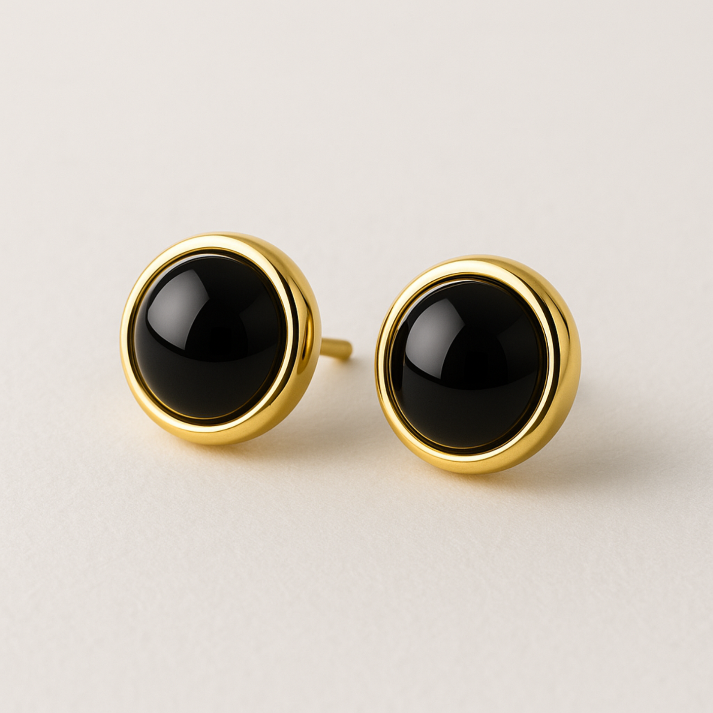 Pair of gold earrings with black stones on a light background