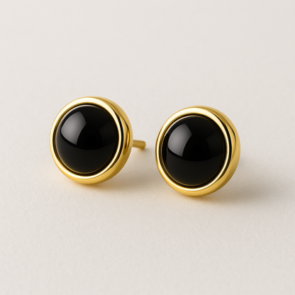 Pair of gold earrings with black stones on a light background