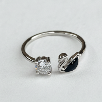 Silver ring with diamond and swan design on a light gray background