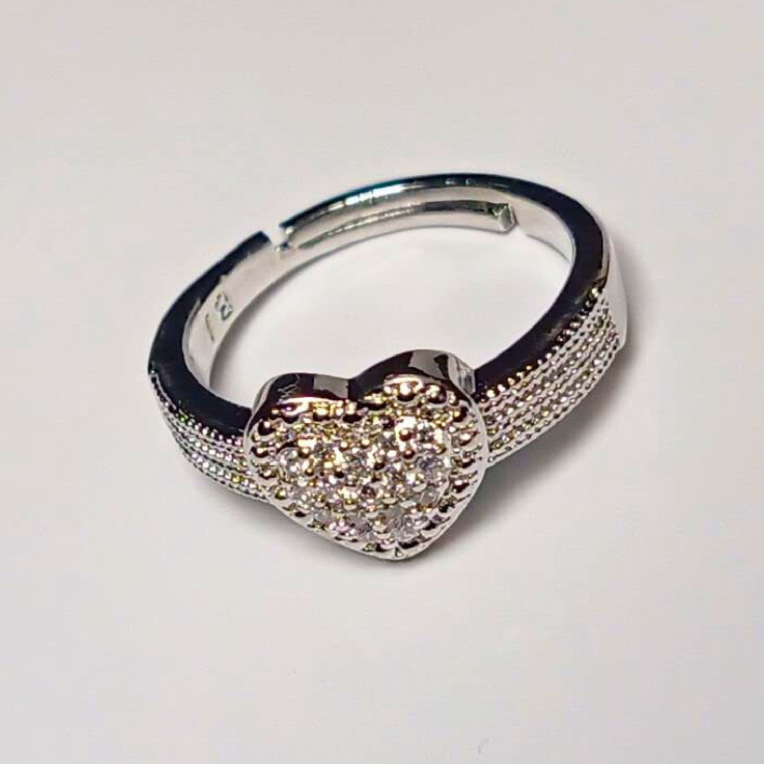 Silver hoop earring with a heart-shaped gemstone on a light gray background