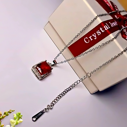 Pendant with red gemstone on a white surface with 'Crystal Jewel' ribbon.
