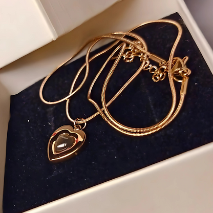 Gold necklace with a heart-shaped pendant on a dark blue velvet surface.