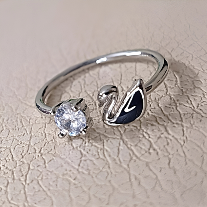 Silver ring with a diamond and black gemstone on a textured beige background