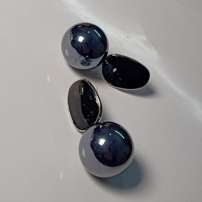 Pair of silver earrings with dark black stones on a white surface
