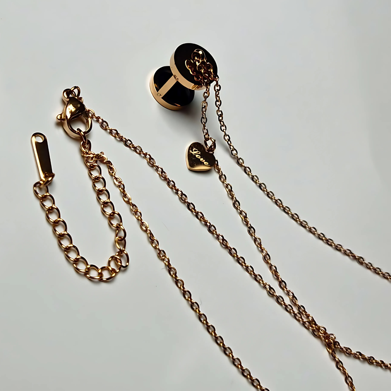 Gold chain with heart-shaped clasp on a light gray background