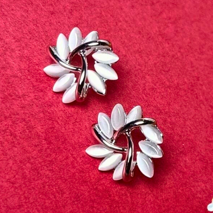Pair of earrings with white floral designs on a red background